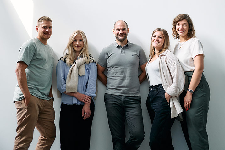 Eine lächelnde Gruppe von Mitarbeitern der Treuhand Hannover lächelt in die Kamera.